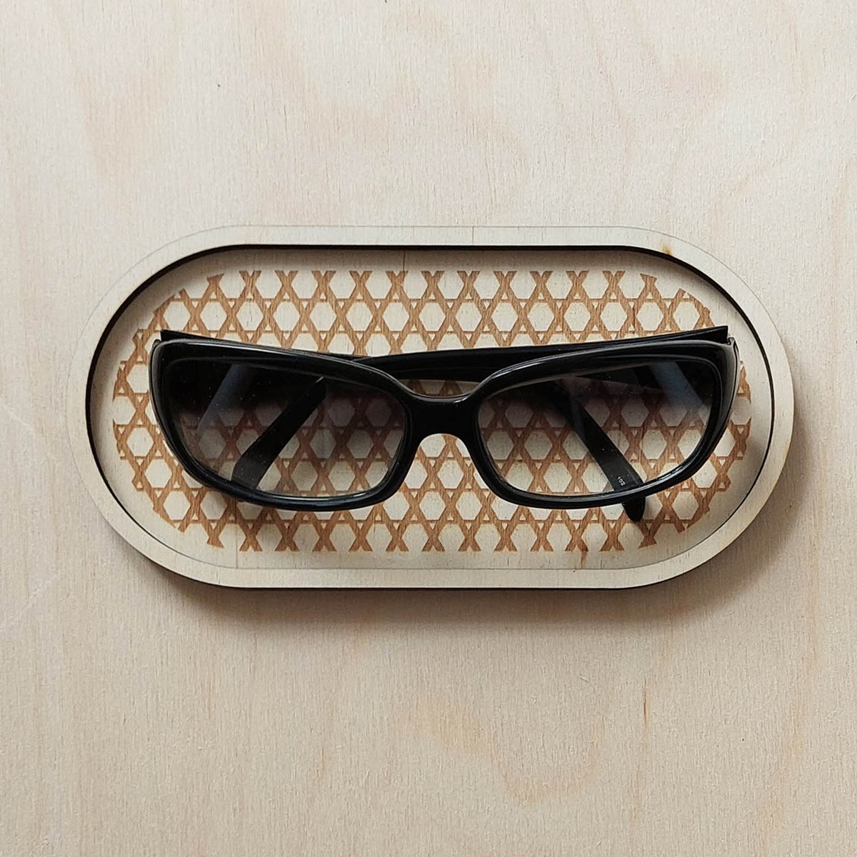 plateau de présentation vide-poche de forme ovale en bois gravé pour bijoux et accessoires, avec une paire de lunettes